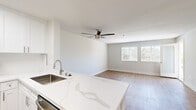 This thoughtfully designed single-floor residence offers a cohesive, modern aesthetic throughout its efficiently utilized layout. The open-concept kitchen and living area serves as the heart of the home, where a striking quartz waterfall-edge peninsula anchors the kitchen. White shaker cabinetry, stainless steel appliances — including a refrigerator, range, and microwave — and a stainless undermount sink complete the kitchen's clean, contemporary look. The living area flows seamlessly from the kitchen, featuring light wood-tone flooring, a ceiling fan, and a large window that frames views of lush greenery, including palm trees visible in the distance.

The spacious primary bedroom is finished with plush carpet, a ceiling fan with integrated lighting, and a window that fills the room with natural light. An exterior door in the bedroom opens to a private balcony overlooking verdant tree canopy, adding a tranquil outdoor connection. The full bathroom is outfitted with a tub-shower combination, a white vanity with a marbled countertop, and wood-look tile flooring, maintaining the home's clean and neutral palette.

Throughout the residence, neutral wall tones, consistent trim work, and an abundance of natural light create a bright, airy ambiance that feels welcoming and move-in ready.