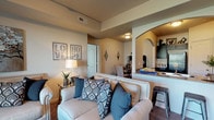 This single-story residence offers a thoughtfully designed layout that balances comfort and functionality across its living spaces. The living room serves as a welcoming centerpiece, featuring plush carpeting, neutral warm-toned walls, and a sliding glass door that opens to a private balcony overlooking a landscaped outdoor area. An arched passageway connects the living area to the kitchen, which is outfitted with dark cabinetry, granite-style countertops, wood-look flooring, and a full suite of black appliances including a refrigerator, range, and microwave. Adjacent to the kitchen, a dedicated dining area accommodates a round table and provides a cozy space for meals. The primary bedroom offers generous proportions with carpet flooring, natural light from multiple windows, and access to a spacious walk-in closet equipped with built-in wire shelving. A secondary bedroom provides a versatile, comfortable space with its own closet. The bathroom features wood-look flooring, a vanity with dark cabinetry, a large mirror with overhead lighting, and a full bathtub with shower. Throughout, the residence maintains a cohesive, inviting ambiance defined by warm neutral tones and consistent finishes.