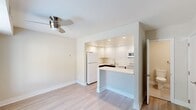 This two-story home in Newark, Delaware offers a clean, modern aesthetic across two thoughtfully laid-out floors. The main level features light-toned hardwood-style flooring throughout the open living and dining area, which is brightened by a large window fitted with blinds and complemented by a ceiling fan. A staircase with a sleek metal railing connects both levels, adding a contemporary architectural touch. The kitchen is efficiently designed with high-gloss white cabinetry, a subway tile backsplash, white appliances including a refrigerator, electric range, microwave, and dishwasher, as well as a peninsula with a white countertop that opens to the main living space. A half bathroom on the main floor provides added convenience. Upstairs, the spacious primary bedroom features plush carpeting and a large walk-in closet with built-in shelving. The second bedroom is equally comfortable, also carpeted, with a standard closet featuring a hanging rod. Both bedrooms share access to a well-appointed full bathroom, finished with large-format tiles, a tub-shower combo with glass enclosure, and a white vanity with modern hardware. A dedicated laundry room on the upper level houses a full-size Whirlpool washer and dryer with overhead wire shelving. Neutral tones and clean finishes give the entire home a bright, move-in-ready appeal.