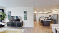 Located at 1230 Vintage Ln in Morgan Hill, California, this single-story home offers a well-designed, open-concept layout with modern finishes throughout. The living area features light wood-tone flooring, crisp white walls, and ample natural light streaming through multiple windows, creating a bright and welcoming atmosphere. The space flows seamlessly into the kitchen, which is appointed with two-tone cabinetry — combining white upper cabinets with dark lower cabinets — a white quartz island with bar seating, a mosaic tile backsplash, and stainless steel appliances including a gas range, microwave, and refrigerator. Recessed lighting illuminates the kitchen and adjoining areas effectively. The bedrooms are generously proportioned, each featuring wood-tone flooring, large windows with outdoor views of surrounding greenery, and clean, neutral wall tones. The bathroom includes wood-look tile flooring, a vanity with storage, and a full tub-and-shower combination. A smart thermostat is visible near the kitchen entry, reflecting the home's modern conveniences. The attached garage offers a spacious, clean interior with an epoxy-coated floor, automatic opener, and fluorescent lighting, providing substantial storage and parking capacity.