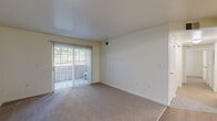 Located in West Jordan, Utah, this two-bedroom, two-bathroom residence offers a practical and well-organized single-floor layout. The combined kitchen and living room serves as the heart of the home, with the living area featuring soft wall-to-wall carpeting and a sliding glass door that opens to a private balcony, filling the space with natural light and outdoor views of surrounding greenery. The kitchen is equipped with warm oak cabinetry offering generous storage, a full suite of white appliances including an electric range, refrigerator, and dishwasher, laminate countertops, and light wood-style flooring. Track lighting adds a functional touch overhead. The primary bedroom is a comfortable retreat with plush carpeting, a large closet with double bi-fold doors, and easy access to one of the two full bathrooms. The second bedroom features carpeted floors, a window with blinds, and a panel door with a brass handle. Both bathrooms are finished with wood-toned vanity cabinetry, light wood-style tile flooring, and a full tub-shower combo with white tile surround and chrome fixtures. A hallway connects the rooms efficiently, and a dedicated closet provides additional storage. Neutral walls and clean finishes throughout give the space a bright, move-in-ready feel.