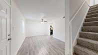 Located at 10611 SR-204 W in Savannah, Georgia, this two-story home presents a clean, neutral aesthetic throughout its well-organized floor plan. Light wood-style luxury vinyl flooring runs through the main living areas, providing a bright, cohesive look that complements the crisp white walls and white trim found throughout the home.

The main level includes a living area with a ceiling fan and textured ceiling, along with a separate room featuring sliding glass doors that open directly to a fenced backyard—offering a practical connection to outdoor space. The kitchen is equipped with white cabinetry, speckled countertops, a double-basin stainless steel sink, and a black dishwasher, combining function with a tidy, classic style.

A bathroom on the main level features a single vanity with speckled countertops and brushed nickel fixtures. Upstairs, the bedrooms are finished with wall-to-wall carpeting and ceiling fans, with multiple windows allowing natural light and neighborhood views. Bedroom closets provide practical storage, and a full bathroom upstairs includes a shower-tub combination, toilet, and vanity with a large mirror. Ceiling fans are present in every room, ensuring comfort throughout the home year-round.