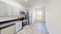 Located at 3040 W Washington St in Stephenville, TX, this two-bedroom, two-bathroom two-story home offers a clean, modern aesthetic across two well-organized floors. The larger main floor hosts an open-concept living, dining, and kitchen area, creating a cohesive and functional shared space. The kitchen is outfitted with stainless steel appliances—including a range, microwave, and refrigerator—complemented by gray shaker-style cabinetry, dark granite countertops with a tile backsplash, and a peninsula that separates the kitchen from the living and dining areas. Wood-look plank flooring runs throughout both levels, lending warmth and visual continuity to the interior. The bathrooms echo the kitchen's design language, featuring the same gray cabinetry, granite countertops, and wood-look flooring. Both bedrooms are bright and well-proportioned, with windows that bring in natural light and closets for storage. The primary bedroom offers a comfortable, private retreat. The upper floor houses the secondary bedroom and additional spaces, including a hallway and closet. A dedicated laundry area adds everyday convenience. The overall design is contemporary and cohesive, with a neutral color palette of whites and soft grays that creates a clean, move-in-ready atmosphere throughout.