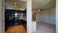 This single-floor residence on Bulverde Road in San Antonio, Texas offers a thoughtfully designed open-concept layout that seamlessly connects the living, dining, and kitchen areas. The living room is generously sized, finished with plush carpet flooring, ceiling fans, and multiple windows fitted with blinds that allow abundant natural light to fill the space. A back door provides direct outdoor access, enhancing the sense of openness.

The kitchen is a standout feature, boasting rich dark espresso cabinetry, granite-style countertops, and a striking mosaic tile backsplash. Black appliances, including a range and over-the-range microwave, complement the warm hardwood-style flooring. A breakfast bar with pendant lighting bridges the kitchen and living area, making it ideal for casual dining or entertaining.

The bedroom is well-proportioned, carpeted, and brightened by dual windows with a ceiling fan overhead. It is complemented by a spacious walk-in closet outfitted with multi-tier wire shelving for ample storage. The bathroom features dark cabinetry with granite-style countertops, a tiled tub-shower combination with a decorative accent border, and tile flooring.

A dedicated laundry room with hardwood-style flooring and wire shelving accommodates a full-size washer and dryer. Throughout, the warm neutral palette and cohesive finishes create a comfortable and functional living environment.