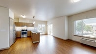 Located at 488 NE Bellevue Dr in Bend, Oregon, this two-bedroom, two-bathroom residence offers a well-designed single-floor layout with a clean, modern aesthetic throughout. The open-concept living area seamlessly connects the kitchen, dining, and living spaces, all finished with warm hardwood-style flooring and neutral walls that maximize the sense of light and space. Large windows throughout invite abundant natural light and offer views of surrounding greenery, while a sliding glass door leads to a private balcony. The kitchen is a standout feature, equipped with stainless steel appliances including a range and refrigerator, warm wood cabinetry, granite countertops, and a peninsula island with pendant lighting — ideal for both cooking and casual dining. The two bedrooms are carpeted for comfort; the primary bedroom includes dual closets offering generous storage. Five closets in total ensure ample storage throughout the residence. The two bathrooms are well-appointed — one features a walk-in glass shower, while the other includes a full tub/shower combo, both with granite-topped vanities. Additional conveniences include an in-unit laundry area. The overall ambiance is bright, clean, and functional, reflecting a contemporary Pacific Northwest style.