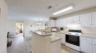 Located at Walden Shores in Brunswick, Georgia, this single-floor, two-bedroom, two-bathroom home offers a well-organized layout designed for comfortable everyday living. Wood-look flooring flows throughout the main areas, connecting each space cohesively. The central hallway provides easy access to all rooms and is flanked by multiple closets, offering generous storage throughout.

The kitchen is a functional highlight, featuring white cabinetry with gold hardware, ample counter space, a double-basin sink, and a peninsula that opens toward the dining and living areas. A pendant chandelier illuminates the dining room, which is finished with the same wood-look flooring and provides a welcoming space for meals. Adjacent to the kitchen, the living room is bright and airy, with a ceiling fan, natural light from a glass exterior door, and views to the outdoors.

The primary bedroom is generously sized, fitted with plush carpet and a walk-in closet outfitted with wire shelving for practical organization. The bathrooms are clean and functional, each featuring a single-sink vanity with white cabinetry and a tub-shower combination. A dedicated laundry room accommodates a full-size washer and dryer side by side. The home's neutral palette and consistent finishes create a calm, move-in-ready atmosphere throughout.