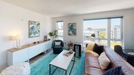 Located at 15400 NE 20th St in Bellevue, Washington, this modern single-floor residence offers a thoughtfully designed layout with clean lines, bright interiors, and elevated views of the surrounding Bellevue neighborhood. The open living area is bathed in natural light from large, expansive windows that frame sweeping views of the cityscape and adjacent rooftops. The space features warm wood-tone flooring that flows throughout the main areas, complementing the contemporary aesthetic. The kitchen is well-equipped with a full suite of stainless steel appliances, including a French door refrigerator, electric range, and over-the-range microwave. Flat-front cabinetry in a soft woodgrain finish pairs with light countertops and a subtle blue glass tile backsplash, creating a sleek, cohesive look. Recessed lighting adds warmth overhead. The bedrooms are carpeted for comfort and filled with natural light through generously sized windows overlooking the neighborhood. One bedroom features a walk-in closet and en-suite access, while the clean white walls throughout provide a neutral canvas. The overall ambiance of the residence is modern, airy, and inviting, well-suited for those seeking contemporary urban living in the heart of Bellevue.