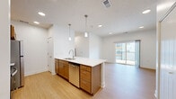 This thoughtfully laid-out one-bedroom, one-bathroom residence in Blair, Nebraska offers a clean, contemporary living experience across a single floor. The modern kitchen is a standout feature, showcasing warm-toned cabinetry, stainless steel appliances including a range, microwave, and refrigerator, and a crisp white subway tile backsplash. A large kitchen island with a built-in sink and sleek countertop provides ample workspace and serves as a natural gathering point. Light wood-look flooring runs throughout the kitchen and main living areas, lending warmth and continuity to the space. The bedroom is a comfortable, well-proportioned retreat finished with plush neutral carpeting, bright white walls, and a ceiling fan with lighting. A window allows natural light to fill the room. The full bathroom is efficiently designed, featuring warm wood-toned cabinetry, a white countertop vanity, a full tub-shower combination, and coordinating light wood-look flooring that mirrors the rest of the unit. Clean white walls and modern brushed nickel hardware complete the polished look. The overall aesthetic is bright, neutral, and move-in ready, making this Blair residence a practical and attractive living space.