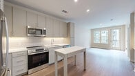 Located at 1201 N Arthur Ashe Blvd in Richmond, VA, this thoughtfully designed one-bedroom, one-bathroom residence offers a clean, contemporary aesthetic throughout. The open-concept kitchen and living area serves as the heart of the home, featuring gray flat-front cabinetry reaching to the ceiling, a white subway tile backsplash, stainless steel appliances including a range, microwave, dishwasher, and refrigerator, and a central island that provides additional prep and dining space. Light wood-tone flooring flows seamlessly throughout, lending warmth and cohesion to the interior. The living area is bright and airy, benefiting from natural light streaming through large windows and a glass-panel door that opens to a private balcony overlooking the surrounding community. The bedroom is a comfortable, well-proportioned retreat with its own windows framing neighborhood views. The bathroom features a full soaking tub with a tiled surround and curved shower rod, paired with neutral tile flooring for a clean, modern finish. Additional practical spaces include a dedicated laundry area, a utility room, and three closets offering generous storage throughout. Recessed lighting and neutral wall tones complete the polished, move-in-ready feel of this well-appointed Richmond residence.