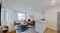 This well-appointed single-floor residence offers a thoughtfully designed open-concept layout that seamlessly connects the kitchen, dining, and living areas. The kitchen is a functional highlight, featuring white shaker cabinetry with gold hardware, a classic subway tile backsplash, granite countertops, and a full suite of stainless steel appliances including a refrigerator, range, dishwasher, and built-in microwave. A granite-topped kitchen island with bar seating provides additional prep and dining space while anchoring the transition into the living area.

The living room is bright and inviting, benefiting from multiple windows that allow ample natural light to fill the space. Light wood-style flooring runs consistently throughout, lending a cohesive and modern aesthetic. A wall-mounted television and dedicated desk area add practical versatility to the living space.

The bedroom is a calm retreat, featuring large windows with outdoor views, wood-tone flooring, and generous space for furnishings. The bathroom includes a full soaking tub with a tiled surround, offering a clean and neutral palette. Recessed lighting and a neutral color scheme throughout the unit contribute to an overall atmosphere that is contemporary, comfortable, and move-in ready.