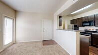 This 1-bedroom, 1-bathroom unit offers a practical and efficient single-floor layout designed for comfortable everyday living. The open-concept living area greets you at the front entry, featuring neutral-toned carpet, clean white walls, and a ceiling fan that enhances airflow and comfort. A pass-through counter connects the living space to the kitchen, creating a seamless flow between the two areas.

The kitchen is well-equipped and functional, showcasing rich dark espresso cabinetry, granite-style countertops, and stainless steel appliances including a range, microwave, and refrigerator. Wood-look flooring runs throughout the kitchen, adding warmth and visual contrast to the space.

The bedroom is a comfortable retreat, carpeted for coziness and fitted with a ceiling fan and a window with blinds that allows natural light to filter in. A private door provides additional access or closet space adjacent to the room.

The bathroom features a full tub and shower combination with white tile surround and chrome fixtures, complemented by tile flooring. A dedicated laundry area houses washer and dryer hookups alongside the water heater and electrical panel, providing all essential utilities in one convenient space. The unit's neutral palette and functional design make it a versatile and move-in-ready home.