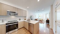 This thoughtfully designed one-bedroom, one-bathroom unit in the 94597 zip code offers a modern aesthetic throughout its efficiently organized single-floor layout. The open-concept kitchen and living area serves as the heart of the home, where light wood-grain cabinetry, a marble-style tile backsplash, and stainless steel appliances—including a range, over-the-range microwave, dishwasher, and French door refrigerator—create a sleek, contemporary kitchen. A peninsula island with a built-in sink and seating provides additional workspace and casual dining. Recessed lighting and warm hardwood-style flooring carry throughout the main living space, which is brightened by large windows that draw in abundant natural light. The living area offers a comfortable, airy atmosphere with views to the outside through a glazed door. The bedroom is a quiet retreat with a window, neutral white walls, and direct access to the walk-in closet, which features adjustable shelving and hanging rods. The bathroom is finished with large-format marble-look tile flooring, a floating wood vanity with a white countertop, a wide mirror, and a full soaking tub with shower. In-unit laundry is also included, adding everyday convenience.