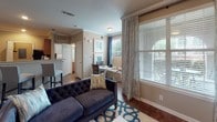This single-floor unit offers a thoughtfully designed layout that maximizes functionality across one bedroom and one bathroom. The living area features hardwood-style flooring, crown molding, and large windows dressed with elegant draping curtains that invite natural light and outdoor views. A ceiling fan with a light fixture adds both comfort and style to the space.

The kitchen is well-equipped with rich wood cabinetry, granite-style countertops, stainless steel appliances including a range, built-in microwave, and a double sink. The warm wood tones of the cabinetry contrast nicely with the lighter countertops, creating an inviting cooking environment.

The bedroom is a restful retreat, featuring hardwood-style flooring, crown molding, a ceiling fan, and a large window that fills the room with natural light. A walk-in closet provides ample storage. The full bathroom includes a tub/shower combination, wood cabinetry, and a window for natural ventilation.

A dedicated laundry area with a full-size washer and dryer adds everyday convenience. Throughout the unit, neutral tones, crown molding, and consistent flooring create a cohesive and comfortable living environment.