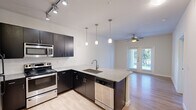 Located at 9301 Old Bee Caves Rd in Austin, TX, this one-bedroom, one-bathroom residence offers a well-designed layout across a single floor. The open-concept kitchen is a standout feature, equipped with dark espresso cabinetry, granite countertops, stainless steel appliances including a refrigerator, electric range, microwave, and dishwasher, and a central peninsula with an undermount sink. Track lighting and elegant pendant lights illuminate the kitchen, which flows seamlessly into the living area. The living space features light wood-style flooring, a ceiling fan, and French doors that invite natural light and provide access to an outdoor area with views of surrounding greenery. The bedroom is carpeted for comfort, features a ceiling fan, and includes a large window with an outdoor view, offering a bright and peaceful retreat. A dedicated closet provides convenient storage. The bathroom is finished with wood-style flooring, dark cabinetry with a granite-topped vanity, and a full tub-shower combination with white tile surround. Clean white walls and consistent modern finishes throughout create a cohesive and contemporary living environment.