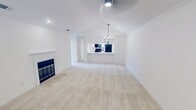 Located at 9000 W Wilderness Way in Shreveport, Louisiana, this single-floor, two-bedroom, three-bathroom residence offers a well-organized layout with clean, contemporary finishes throughout. The interior is characterized by crisp white walls, crown molding, and a neutral color palette that creates a bright, cohesive atmosphere from room to room.

The living room serves as a central gathering space, anchored by a classic wood-burning fireplace with a white mantel and complemented by plush carpeting and recessed lighting. The adjacent kitchen features an open pass-through design with quartz-style countertops, white cabinetry, and a suite of black stainless steel appliances including a range, microwave, and refrigerator — a functional and stylish setup for everyday cooking.

The generously sized primary bedroom includes crown molding, a ceiling fan, and access to a spacious walk-in closet outfitted with dual hanging rods and shelving. The en-suite primary bathroom showcases a long double-vanity with white cabinetry, stone countertops, matte black hardware, and wood-look flooring. The second bedroom also features a ceiling fan and natural light from a window. All three bathrooms maintain consistent finishes, including white vanities and matte black fixtures. The entryway welcomes residents with a pendant light fixture and a security panel.