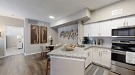 This single-story 2-bedroom, 3-bathroom residence offers a well-planned layout that maximizes functionality across a comfortable footprint. The open-concept kitchen, dining, and living area serves as the heart of the home. The kitchen features granite countertops, a center island with bar seating, crisp white cabinetry, stainless steel appliances, a subway tile backsplash, and wood-look flooring. The adjacent dining nook is framed by decorative wall art, creating a defined yet connected space. The living room offers a ceiling fan, natural light from large windows, and wood-look flooring that continues throughout the main area. Both bedrooms are carpeted and include ceiling fans and windows providing natural light. The primary bedroom is generously sized and connects to a full bathroom featuring a granite vanity, white cabinetry, and a soaking tub with shower. A walk-in closet with built-in shelving and hanging rods provides ample storage. Two additional closets and a hallway connecting the rooms add to the home's practical layout. With three full bathrooms, neutral tones, and consistent modern finishes throughout, this residence delivers a clean, comfortable, and well-organized living environment.