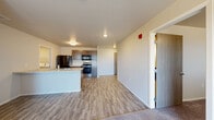 Located at 1330 Catron Blvd in Rapid City, South Dakota, this single-floor unit offers a thoughtfully designed open-concept layout that seamlessly connects the kitchen, dining, and living areas. The kitchen is a functional centerpiece, featuring dark wood cabinetry, light countertops, a central island with a built-in sink, and a full suite of appliances including a stainless steel electric range, over-the-range microwave, and black refrigerator. Light wood-style luxury vinyl plank flooring runs throughout the main living and kitchen areas, providing a clean and contemporary look, while plush carpeting adds comfort to the living and bedroom spaces. The living area is generously sized with large windows that invite natural light. A dedicated laundry area houses a full-size washer and dryer. The bathroom includes wood-style flooring, a dark vanity with storage, and a shower-tub combo, while a second bathroom offers a vanity and access to a walk-in closet with built-in shelving. The unit's neutral color palette, clean lines, and practical layout make it a versatile and move-in ready space.