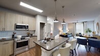 Located in Yulee, FL, this well-appointed single-story residence offers a thoughtfully designed open-concept layout that seamlessly connects the kitchen, dining, and living areas. The kitchen is a standout feature, outfitted with light wood cabinetry, a subway tile backsplash, stainless steel appliances — including a French door refrigerator, microwave, and range — and a generously sized island with a dark quartz countertop, undermount sink, and seating for casual dining. Brushed nickel pendant lights illuminate the island, enhancing the modern aesthetic. Hardwood-style flooring flows throughout the main living areas, adding warmth and continuity. The living room is bright and welcoming, benefiting from large windows dressed with elegant drape panels and blinds, a ceiling fan, and ample room for comfortable furnishings. Both bedrooms are carpeted and feature ceiling fans, large windows that invite natural light, and walk-in closets with built-in wire shelving. The bathrooms are finished with light wood vanities, dark quartz countertops, and large mirrors with contemporary vanity lighting; the primary bath includes a glass-enclosed walk-in shower with white subway tile. A dedicated pantry with built-in shelving adds practical storage to this polished and cohesive home.