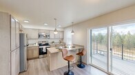 Located at 13809 E Carlisle Ave in Spokane Valley, Washington, this well-appointed single-floor residence combines modern design with functional living. The entryway welcomes you with light wood-style flooring, soaring walls, and a wall-mounted mini-split HVAC unit for year-round comfort.

The kitchen is a standout feature, outfitted with light wood cabinetry, quartz-style countertops, stainless steel appliances including a range, microwave, refrigerator, and dishwasher, and a central island with bar seating. Stylish pendant lighting illuminates the space, while multiple windows and a sliding glass door to the private balcony flood the area with natural light and offer views of surrounding trees and open sky.

The living room is bright and airy, benefiting from tall windows — including a transom-style upper window — that fill the space with abundant daylight and enhance the sense of volume.

A dedicated office or flex room features carpeted flooring and a large window overlooking the exterior, making it ideal for remote work or study. The bathrooms are clean and modern, with one featuring a soaking tub and light wood vanity, and another with a glass-enclosed shower. Bedrooms are carpeted and well-lit with natural light from well-placed windows throughout.