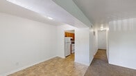 Located in the Fields neighborhood of Indianapolis, Indiana, this single-floor residence offers a practical and well-organized layout with two bedrooms and two full bathrooms. The interior is designed for functionality, with a clear distinction between living and private spaces connected by a central hallway.

The living and dining area features neutral tile flooring and white walls, creating a bright, open feel. It connects directly to the kitchen, which is equipped with warm-toned wooden cabinetry, dark countertops, and white appliances including a refrigerator, electric range, and dishwasher. Tile flooring continues throughout the kitchen, adding to the cohesive look of the common areas.

Both bedrooms are finished with wall-to-wall carpet and white walls. The primary bedroom is a generously sized room featuring two windows that allow natural light to fill the space. The second bedroom is more compact but equally well-lit and comfortable.

The two bathrooms each feature a tub-shower combination with white surround panels, tile flooring, and wooden vanity cabinetry with light countertops. The layout also includes a dedicated closet and entrance area, adding to the overall storage and convenience of the home. Clean finishes and a neutral color palette are consistent throughout the space.