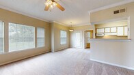 Located at 5000 Clinton Pkwy in Lawrence, Kansas, this 2-bedroom, 1-bathroom single-floor residence offers a well-organized and functional layout. The combined living, dining, and kitchen area forms the heart of the home, featuring plush carpeting, crown molding, and ceiling fans throughout. Multiple windows allow natural light to fill the living and dining spaces, creating a bright and welcoming atmosphere. A pendant light fixture highlights the dining area, which also benefits from direct access to the outdoors through a private exterior door with sidelight windows.

The galley-style kitchen is equipped with white cabinetry, a full suite of white appliances including a range, refrigerator, dishwasher, and microwave, all set above warm hardwood flooring. A pantry closet provides additional storage within the kitchen.

Both bedrooms are generously proportioned, carpeted, and finished with neutral tones. The primary bedroom features a ceiling fan and a bank of windows that invite natural light, while both rooms include closets for storage. The bathroom continues the hardwood flooring found in the kitchen and hallway, and includes a soaking tub, vanity with mirror, and towel bar. Two additional closets throughout the unit provide practical storage solutions.