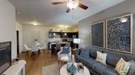 This single-floor residence offers a thoughtfully designed open-concept layout that seamlessly connects the living, dining, and kitchen areas. The living room is a bright, welcoming space highlighted by large windows that invite abundant natural light, a ceiling fan, and wood-style flooring that extends throughout the main living areas. The kitchen is a standout feature, outfitted with dark cabinetry, granite-style countertops, stainless steel appliances including a refrigerator, dishwasher, and microwave, along with a kitchen island that provides additional prep and seating space. Pendant lighting adds a refined touch overhead.

The residence includes two bedrooms, each with ceiling fans and plush carpeting. The primary bedroom is generously sized, while the second bedroom also benefits from natural light through well-appointed windows. Both bathrooms feature dark vanity cabinetry with granite-style countertops and tub-shower combinations with tile surrounds, finished with wood-style flooring.

Additional conveniences include a dedicated in-unit laundry space with a full-size washer and dryer, as well as closet storage accessible from the main living area. The neutral gray color palette and consistent finishes throughout give the space a cohesive and modern ambiance.