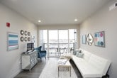 This single-floor unit blends industrial design elements with comfortable living spaces. The kitchen is a standout feature, showcasing warm wood cabinetry, stainless steel appliances including a refrigerator, electric range, and microwave, all complemented by a white countertop island with bar seating. Exposed ductwork runs along the ceiling, adding an urban, loft-inspired character, while pendant lighting reinforces the industrial aesthetic. The open living area flows seamlessly from the kitchen and is filled with natural light through large sliding glass doors that lead to a private balcony, offering open outdoor views.

The unit includes two bedrooms, each equipped with ceiling fans and carpeted flooring. One bedroom features a large window with an exterior view, while the other benefits from a built-in open closet system. Both bathrooms are finished with wood-toned cabinetry, white countertops, and wood-look flooring, providing a clean and cohesive look. A dedicated laundry area houses a full-sized washer and dryer, adding everyday convenience. Throughout the unit, neutral wall tones create a calm, versatile backdrop.