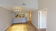 This single-floor residence offers a thoughtfully designed layout that balances comfort and functionality. The open-concept living area is anchored by warm hardwood-style flooring and crown molding, creating an inviting atmosphere throughout. A peninsula kitchen overlooks the living space and is outfitted with gray cabinetry, light stone-look countertops, a stainless steel refrigerator, gas range, and built-in microwave — providing ample storage and a modern aesthetic. Track lighting above the kitchen peninsula adds focused illumination to the living area.

The bedrooms feature plush carpeting and generous proportions, with at least one room showcasing vaulted ceilings and a ceiling fan, as well as a window that allows natural light to filter in. A walk-in closet with wire shelving provides substantial storage capacity.

The bathrooms are finished with hardwood-style flooring, gray vanity cabinetry, stone-look countertops, and a tiled shower-tub combination, delivering a clean and cohesive look. White panel doors and consistent neutral-toned walls throughout the residence tie each space together, creating a unified and well-maintained interior from room to room.