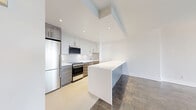 Located on Cedar Avenue in the heart of Montréal, this well-appointed one-bedroom, one-bathroom unit offers a comfortable and thoughtfully designed layout across a single floor. The living room is bright and welcoming, featuring distinctive parquet flooring in a checkerboard pattern and large windows that open onto a balcony, allowing generous natural light and pleasant outdoor views of the surrounding greenery. The modern kitchen is efficiently designed with a galley-style layout, showcasing white upper cabinetry, warm wood-toned lower cabinets, white quartz countertops, a tile backsplash, and stainless steel appliances including a built-in range and refrigerator. A breakfast bar with matching wood-panel detailing provides additional counter space and a casual dining option. The spacious primary bedroom continues the parquet flooring theme, offering a clean, neutral palette and a built-in closet. The bathroom is elegantly finished with floor-to-ceiling marble-effect wall tiles surrounding the bathtub, light tile flooring, and a crisp white vanity. A welcoming hallway connects all areas of the unit, completing this clean and modern home.
