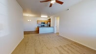 Located on Berthoud Parkway in Loveland, Colorado, this single-floor unit offers a thoughtfully designed open-concept layout. The living and dining area flows seamlessly into the kitchen, where warm knotty pine cabinetry, dark granite-style countertops, and a full suite of stainless steel appliances—including a range, microwave, refrigerator, and dishwasher—create a functional and inviting space. A peninsula with an undermount sink and breakfast bar separates the kitchen from the carpeted living area, which is accented by a ceiling fan and an elegant chandelier in the dining nook. Wood-look vinyl flooring runs through the kitchen and entry areas, providing a clean contrast to the plush carpet found throughout the rest of the unit. The bedrooms are generously sized, each featuring ceiling fans or ample natural light from large windows with blinds. The primary bedroom benefits from abundant windows, filling the room with sunlight and views of the surrounding area. The bathroom includes a full tub-shower combo with built-in shelving, wood-look flooring, warm wood cabinetry with a dark countertop vanity, a large mirror, and direct access to a spacious walk-in closet with built-in shelving and hanging rods. The overall ambiance is clean, bright, and move-in ready.