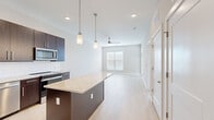 Located at 1110 Metropolitan Ave in Summerville, SC, this well-appointed one-bedroom, one-bathroom residence offers a thoughtfully designed single-floor layout with modern finishes throughout. Light wood-tone flooring flows seamlessly across the open-concept living and kitchen areas, creating a bright and cohesive aesthetic.

The kitchen is a standout feature, showcasing rich dark espresso cabinetry that extends to the ceiling, granite countertops, a large center island with pendant lighting overhead, and a full suite of stainless steel appliances including a refrigerator with ice maker, electric range, built-in microwave, and dishwasher. A white tile backsplash adds a clean, contemporary touch.

The open living area extends naturally from the kitchen and benefits from a ceiling fan, recessed lighting, and a window that allows natural light to fill the space. The bedroom is comfortably sized with multiple windows, a ceiling fan, and direct access to a dedicated closet.

The bathroom is finished to a high standard, featuring a dark vanity with granite countertop, a large frameless sliding glass shower-tub combination, and modern brushed nickel fixtures. Neutral wall tones throughout the residence contribute to a calm, inviting atmosphere well-suited for comfortable everyday living.