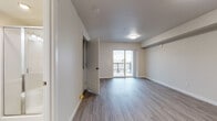 This well-appointed single-floor unit offers a clean, contemporary design with a neutral color palette and wood-look plank flooring that flows consistently throughout the space. The open living area is bright and spacious, anchored by sliding glass doors that lead to a private balcony with outdoor views of the surrounding neighborhood and greenery, allowing natural light to fill the room. A second bedroom or flex room features a large window with expansive neighborhood views and an integrated wall heater. The galley-style kitchen is thoughtfully designed with dark wood cabinetry, open shelving, light countertops, a stainless steel appliance suite including a refrigerator, range, and dishwasher, and a functional single-basin sink. A dedicated pantry closet adds extra storage convenience. The unit includes two bathrooms: one with a full soaking tub and bright surround, and another with a standalone glass-enclosed shower stall, a vanity with wood cabinetry, and stone-look tile flooring. A dedicated in-unit laundry closet with a stacked washer and dryer provides added convenience. Additional storage is accessible via a walk-in closet. The overall ambiance is modern, clean, and move-in ready.