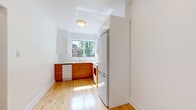 Located on Avenue Decelles in the Côte-des-Neiges neighbourhood of Montréal, this well-appointed one-bedroom, one-bathroom unit offers a thoughtfully organized layout across a single floor. Warm hardwood flooring flows consistently throughout the living areas, hallway, bedroom, and kitchen, lending the space a cohesive and inviting character.

The living room is generously sized, featuring two large windows that frame views of lush greenery and neighbouring brick architecture, while baseboard radiators beneath each window provide efficient heating. The bright and airy atmosphere is complemented by neutral grey-toned walls throughout.

The kitchen is efficiently designed in an L-shaped configuration, showcasing warm honey-toned wood cabinetry paired with white countertops and appliances, including a dishwasher, stove, and full-size refrigerator. A window above the sink invites natural light and offers pleasant outdoor views.

The bedroom is a comfortable, well-proportioned room with a large window overlooking greenery, ensuring ample natural light. It features a closet and connects easily to the rest of the unit via a hallway with clean-lined white panel doors.

The bathroom is finished in crisp white tile, equipped with a full soaking tub, toilet, and a wall-mounted sink, with a frosted window providing natural light and privacy. The entrance and hallway complete the layout, offering a practical transition into the living spaces.