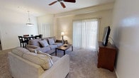Located at 2400 E Llano Estacado Blvd in Clovis, New Mexico, this single-floor residence offers a comfortable and well-designed living space with a warm, neutral aesthetic throughout. The living room serves as the heart of the home, featuring plush wall-to-wall carpeting and a ceiling fan that adds both style and function. Large sliding glass doors dressed with vertical blinds allow generous natural light to fill the room while providing access to the outdoors. Structural beam detailing along the ceiling adds a subtle architectural character to the space. The open-concept layout allows the living room to flow naturally into the dining area, which is illuminated by a hanging pendant light, creating a cohesive and inviting atmosphere ideal for both everyday living and entertaining. The overall ambiance is bright and airy, with light-toned walls that complement the neutral carpeting and contribute to a clean, welcoming feel throughout. The thoughtful layout and quality finishes make this a functional and comfortable single-level home in the heart of Clovis, NM.