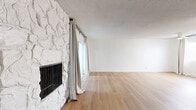 Located on Rose Avenue in the heart of West Los Angeles, this one-bedroom, one-bathroom unit offers a well-organized layout across a single floor. Light-toned hardwood flooring runs throughout the entire space, creating a warm and cohesive feel from room to room.

The open living room serves as the centerpiece of the unit, highlighted by a striking white stone fireplace accent wall and a sliding glass door that opens onto a private balcony overlooking lush, tree-lined greenery. Natural light fills the space through large windows dressed with neutral linen-style curtains.

The galley-style kitchen is efficiently designed with white shaker cabinetry featuring matte black hardware, dark countertops, stainless steel appliances including a gas range and refrigerator, and a black matte faucet over a double-basin sink. A window at the end of the kitchen allows additional natural light into the space.

The bedroom is a comfortably sized, bright room with a decorative pendant light fixture and a window with garden-facing views. The bathroom is clean and functional, featuring a tiled tub-shower combination, open wall shelving, and a window for natural ventilation. A hallway connects the rooms and includes a ceiling fan for added comfort throughout.