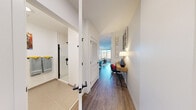 Located along I-90 E in Boston, MA, this thoughtfully designed one-bedroom, one-bathroom unit makes efficient use of its compact footprint across a single floor. A welcoming hallway with warm wood-tone flooring and clean white walls sets the tone upon entry, leading residents through the well-organized layout. The kitchen is a standout feature, boasting two-toned cabinetry — warm wood uppers paired with light lower cabinets — white subway tile backsplash with under-cabinet lighting, stainless steel appliances including a refrigerator, range, and microwave, plus a sink with modern fixtures. A large window floods the kitchen and dining area with abundant natural light and offers views of the surrounding neighborhood. The bedroom is a cozy retreat, featuring the same hardwood-style flooring, room for a full-size bed and a dedicated workspace, and vibrant wall art that adds personality. The bathroom presents a clean, modern aesthetic with a wood-vanity cabinet, white countertop, matte black fixtures, a large mirror, and a glass-enclosed shower. Throughout the unit, consistent wood-tone flooring, crisp white walls, and black hardware details create a cohesive, contemporary feel.