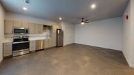 Located along Pinnacle Hills Parkway in Rogers, Arkansas, this single-floor unit offers a clean, contemporary design with consistent finishes throughout. The open-concept main living area is anchored by neutral-toned tile flooring laid in a checkered pattern, recessed lighting, and a ceiling fan, creating a functional and well-lit environment. Windows along one wall allow natural light to fill the space, enhancing its open feel.

The kitchen is outfitted with stainless steel appliances, including an electric range, over-the-range microwave, refrigerator, and dishwasher. Light wood-grain cabinetry with brushed metal hardware pairs with white quartz-style countertops and a tile backsplash, lending a modern, cohesive aesthetic. A stainless steel sink completes the workspace.

The bathroom features a soaking tub and shower combination surrounded by vertically stacked rectangular tile in a warm beige tone. Gray tile flooring, white walls, and a light wood vanity contribute to the clean, neutral palette carried throughout the unit.

A stacked washer and dryer unit is integrated into the living space, offering convenient in-unit laundry. The overall design emphasizes modern simplicity with durable, low-maintenance finishes.