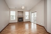 This single-floor space is thoughtfully designed with an open-concept layout that promotes a sense of spaciousness throughout. The living area is a standout feature, showcasing vaulted ceilings and warm hardwood flooring that extends across the main living zones. A tile-surround fireplace is set into a dedicated niche on the accent wall, flanked by windows that allow natural light to fill the room. A ceiling fan overhead and a sliding glass door leading to an outdoor area further enhance the living space's functionality and appeal.

The kitchen is equipped with warm wood cabinetry, granite-style countertops, and black appliances including a range, microwave, and refrigerator. A peninsula with pendant lighting above serves as both a workspace and a casual dining area, connecting seamlessly to the living space. An adjacent pantry or storage closet provides additional organizational space.

A carpeted bedroom offers a ceiling fan and a sliding glass door for natural light and outdoor access. The bathroom includes a full tub and shower combo with tile flooring and a wood-toned vanity. A generously sized walk-in closet with multi-level wire shelving provides ample storage. Rich wood baseboards and trim are consistent throughout, adding a cohesive, polished finish to the interior.
