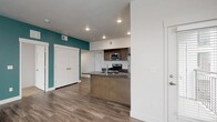 This well-appointed single-floor residence combines contemporary design with functional living spaces. The open-concept layout connects the kitchen and living area seamlessly, with wide-plank wood-look flooring extending throughout the main areas. A bold teal accent wall adds a striking pop of color to the living space, which is bathed in natural light from multiple windows. The kitchen is a standout feature, outfitted with rich dark wood cabinetry, a classic white subway tile backsplash, stone countertops, a peninsula with a built-in sink, and a full suite of stainless steel appliances including a gas range, over-the-range microwave, and refrigerator. The bedrooms offer plush carpeting, ceiling fans, and generous windows that invite natural light. The primary bathroom is equipped with a dual-sink vanity, dark wood cabinetry, a wide mirror, and wood-look flooring. A second full bathroom features a single vanity with matching cabinetry and a shower-tub combination. Additional storage is provided by a double-door closet in the main living area. Recessed lighting throughout completes the clean, modern aesthetic of this thoughtfully designed residence.