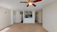This single-floor residence offers a thoughtfully designed open-concept layout that seamlessly connects the living area to the kitchen. The spacious living room is finished with plush neutral carpeting and features a ceiling fan with light fixture, creating a comfortable and airy atmosphere. A wide window allows natural light to fill the room, enhancing its welcoming ambiance.

The kitchen is a standout feature, boasting rich dark cabinetry paired with granite-style countertops and a full suite of black appliances, including a refrigerator, electric range, built-in microwave, and sink. A half-wall peninsula separates the kitchen from the living area, providing both visual distinction and functional counter space. Hardwood-style flooring grounds the kitchen, contrasting beautifully with the cabinetry.

The bedrooms are carpeted and finished in soft neutral tones, each benefiting from natural light through slatted blinds. The layout provides a comfortable sense of privacy for each room.

The primary bathroom features a granite-topped vanity with dark cabinetry, a large mirror, and tile flooring. A second bathroom includes a walk-in shower with built-in shelving and grab bars, tiled flooring, and clean white finishes throughout. Together, the bathrooms reflect a consistent design aesthetic that ties the home together cohesively.