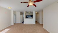 This single-floor residence offers a thoughtfully designed open-concept layout that seamlessly connects the living area to the kitchen. The spacious living room is finished with plush neutral carpeting and features a ceiling fan with light fixture, creating a comfortable and airy atmosphere. A wide window allows natural light to fill the room, enhancing its welcoming ambiance.

The kitchen is a standout feature, boasting rich dark cabinetry paired with granite-style countertops and a full suite of black appliances, including a refrigerator, electric range, built-in microwave, and sink. A half-wall peninsula separates the kitchen from the living area, providing both visual distinction and functional counter space. Hardwood-style flooring grounds the kitchen, contrasting beautifully with the cabinetry.

The bedrooms are carpeted and finished in soft neutral tones, each benefiting from natural light through slatted blinds. The layout provides a comfortable sense of privacy for each room.

The primary bathroom features a granite-topped vanity with dark cabinetry, a large mirror, and tile flooring. A second bathroom includes a walk-in shower with built-in shelving and grab bars, tiled flooring, and clean white finishes throughout. Together, the bathrooms reflect a consistent design aesthetic that ties the home together cohesively.