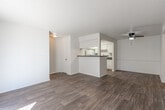 This single-floor residence offers three bedrooms and two full bathrooms within a practical and well-organized floor plan. Wood-look flooring runs consistently throughout the home, providing a cohesive and easy-to-maintain surface across every room.

The combined kitchen and living area forms the heart of the home. The kitchen is laid out in a galley style, featuring white cabinetry with ample upper and lower storage, dark granite-style countertops, white appliances including a range and refrigerator, and a raised breakfast bar that opens toward the living room. The living room is bright and open, highlighted by a sliding glass door dressed with vertical blinds that leads to an outdoor patio and allows generous natural light to fill the space.

Each of the three bedrooms is finished with the same wood-look flooring, neutral walls, a textured ceiling, and a ceiling fan with integrated lighting. Windows with blinds allow natural light into the bedrooms while maintaining privacy. The spacious primary bedroom provides a comfortable retreat.

Both bathrooms are identically appointed, each featuring a tiled tub-shower combo, a toilet, wood-look flooring, and a vanity with dark countertops and a mirror. Grab bars are also present for added accessibility. A hallway and dedicated closet round out the floor plan, offering practical storage and circulation throughout the home.