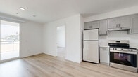 Located on N Van Nuys Blvd in Los Angeles, this thoughtfully designed 3-bedroom, 2-bathroom unit offers a clean, contemporary aesthetic across a single floor. Light wood-look flooring flows seamlessly throughout, complementing crisp white walls and modern trim work that give the space a bright, airy feel.

The kitchen is a functional centerpiece, featuring gray shaker-style cabinetry with matte black hardware, white quartz countertops, a stainless steel refrigerator, range, and dishwasher, as well as a subway tile backsplash — creating a polished and practical cooking environment that opens to the main living area.

The three bedrooms are well-proportioned and filled with natural light from large windows offering views of the surrounding Los Angeles neighborhood, including glimpses of palm trees. The primary bedroom is generously sized and includes mirrored sliding closet doors that enhance the sense of space. Additional bedrooms offer natural light and clean finishes.

Both bathrooms continue the modern design language. One features a full soaking tub with tiled surround, while the other showcases a gray vanity with quartz countertop, an undermount sink, and a large framed mirror. A private balcony extends the living space outdoors, rounding out this well-appointed unit.