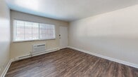 Located at 360 Sandra Ln in Indianapolis, Indiana, this two-bedroom, one-bathroom unit offers a practical and comfortable single-floor layout. Wood-style flooring runs consistently throughout the home, lending a cohesive and easy-to-maintain aesthetic across every room. The living room is a bright, open space featuring a large window with blinds that allows natural light to fill the room, a wall-mounted air conditioning unit, and a baseboard heating system. The kitchen is well-appointed with rich, dark-stained cabinetry, granite-look countertops, and a full suite of black appliances including a refrigerator, electric range, dishwasher, and an over-range exhaust hood. A double-basin sink sits beneath a window, adding natural light to the cooking area. Both bedrooms are comfortably sized with neutral wall tones, wood-style flooring, and windows with blinds that bring in outdoor views and daylight. Ceiling fans with light fixtures are present in the bedrooms, enhancing comfort and airflow. A connecting hallway links the bedrooms to the rest of the unit. The bathroom features a white tiled tub-shower combo, a toilet, and a dark wood vanity, all set on wood-style flooring that ties the space together seamlessly.
