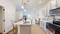 Located in Enola, PA, this single-floor, 2-bedroom, 1-bathroom home offers a thoughtfully designed open-concept layout with a bright, neutral palette throughout. The kitchen is a standout feature, showcasing gray shaker-style cabinetry, quartz countertops, stainless steel appliances, and a central island with a double-basin sink and pendant lighting — ideal for both cooking and casual dining. Light wood-look flooring flows seamlessly from the kitchen into the living room, which features recessed lighting and a sliding glass door that opens to a private balcony with scenic outdoor views. The spacious primary bedroom is carpeted for comfort and includes ample natural light from double windows, while the second bedroom is similarly finished with carpet and a large closet. A dedicated walk-in closet with wire shelving provides generous storage. The full bathroom includes a shower/tub combo with clean, modern finishes and wood-look flooring. Throughout the home, crisp white walls and recessed lighting create a clean, airy ambiance that makes the space feel open and welcoming. The entry area connects efficiently to the kitchen, enhancing the home's practical, functional flow.