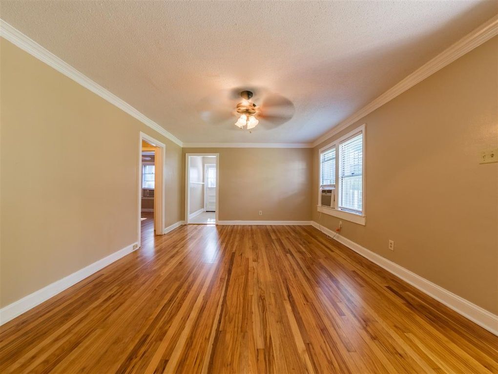 Spacious living room with hardwood floors, ceiling fan, and large AC window unit - 1744 N Parkway