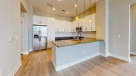 This single-story home in Savannah, GA offers a thoughtfully designed layout across three bedrooms and two bathrooms. The open-concept kitchen and living area serves as the heart of the home, featuring light hardwood-style flooring throughout. The kitchen is outfitted with two-tone cabinetry—white upper cabinets paired with gray lower cabinets—complemented by a white subway tile backsplash, quartz countertops, stainless steel appliances, and a central island with pendant lighting. The living area benefits from abundant natural light and opens directly to an outdoor balcony through elegant French doors with transom windows above.

The primary bedroom is a well-sized retreat with hardwood-style flooring and direct access to a private en-suite bathroom, which features a glass-enclosed walk-in shower with floor-to-ceiling tile and modern black-framed hardware. The secondary bathroom includes a full tiled tub-shower combination and a large window for natural light. The two additional bedrooms are carpeted and feature neutral gray walls, large windows with outdoor views, and white panel doors. Two hallways connect the spaces efficiently, contributing to the home's clean, contemporary aesthetic throughout.