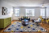 This two-bedroom, one-bathroom residence at The Williamsburg in Memphis, Tennessee offers a well-designed single-floor layout characterized by warm parquet hardwood flooring that runs throughout the living, dining, and bedroom areas. The living room is spacious and bright, benefiting from a row of windows that invite generous natural light and views of the surrounding greenery. A dedicated dining area adjacent to the living space provides a functional and comfortable setting for everyday use.

The kitchen has been thoughtfully updated with gray cabinetry, light granite countertops, a classic white subway tile backsplash, and stainless steel appliances including a gas range, dishwasher, and refrigerator. Marble-look tile flooring and a window above the counter enhance the kitchen's clean, modern aesthetic.

Both bedrooms are comfortably sized, each featuring parquet flooring, ceiling fans, and windows that allow ample natural light. The shared full bathroom includes a tiled tub-shower combination, wainscoting detail, and a window for ventilation. A hallway with a full-length mirror connects the main areas efficiently. Throughout the unit, white walls and abundant window coverage create a bright, airy atmosphere well-suited to comfortable daily living.