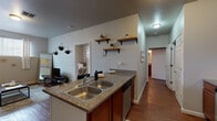 Located at West Elm Avenue in Stillwater, Oklahoma, this single-story residence offers a thoughtfully designed layout with a warm, cohesive aesthetic throughout. Rich hardwood flooring flows seamlessly across the living areas, creating a welcoming and unified feel.

The kitchen is a functional centerpiece, featuring warm wood cabinetry, granite-style countertops, a peninsula island with bar seating, stainless steel appliances including a gas range, microwave, dishwasher, and refrigerator, along with a double-basin sink. Open wall shelving adds both storage and decorative character to the space.

The living room is bright and inviting, with natural light filtering through large windows and neutral walls that lend a clean, modern ambiance. The space comfortably accommodates a full seating arrangement.

The bedrooms are cozy and well-proportioned, each featuring hardwood floors, windows with blinds and curtains for privacy, and ample room for sleeping and study areas. The rooms offer a quiet, functional retreat.

The bathroom is neatly appointed with a wood-toned vanity, granite countertop, a combination tub and shower, and hardwood flooring that carries through from the rest of the home. The overall design of this residence balances practicality with comfortable, everyday livability.