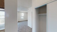 Located at 8525 Tobias Ave in the Panorama City neighborhood of Los Angeles, this single-floor unit offers a functional and straightforward layout designed for comfortable everyday living. The living area is generously sized, featuring wall-to-wall carpeting, a textured ceiling, and abundant natural light streaming in through large windows and a sliding glass door that opens to a balcony. The balcony provides views of the surrounding neighborhood, with palm trees visible in the distance, adding a distinctly Southern California feel. A wall-mounted air conditioning unit ensures year-round comfort in the living space. The galley-style kitchen is efficiently laid out, featuring warm wood-toned upper and lower cabinetry, light countertops, a double-basin stainless steel sink, and wood-look flooring. White appliances including a refrigerator and range complete the kitchen's practical setup. The bedroom offers carpeted flooring, a window with natural light, and a closet with built-in shelving for storage. The bathroom is well-appointed with a single vanity sink, a large mirror with overhead lighting, a toilet, and a full shower-tub combination, all set on rich wood-look flooring. Overall, the unit presents a clean, neutral palette throughout, providing a versatile canvas for personalization.
